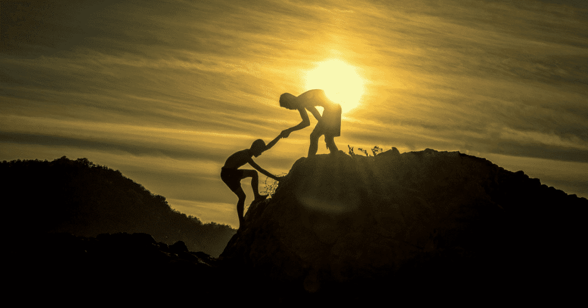 A man helping another man to claim a mountain